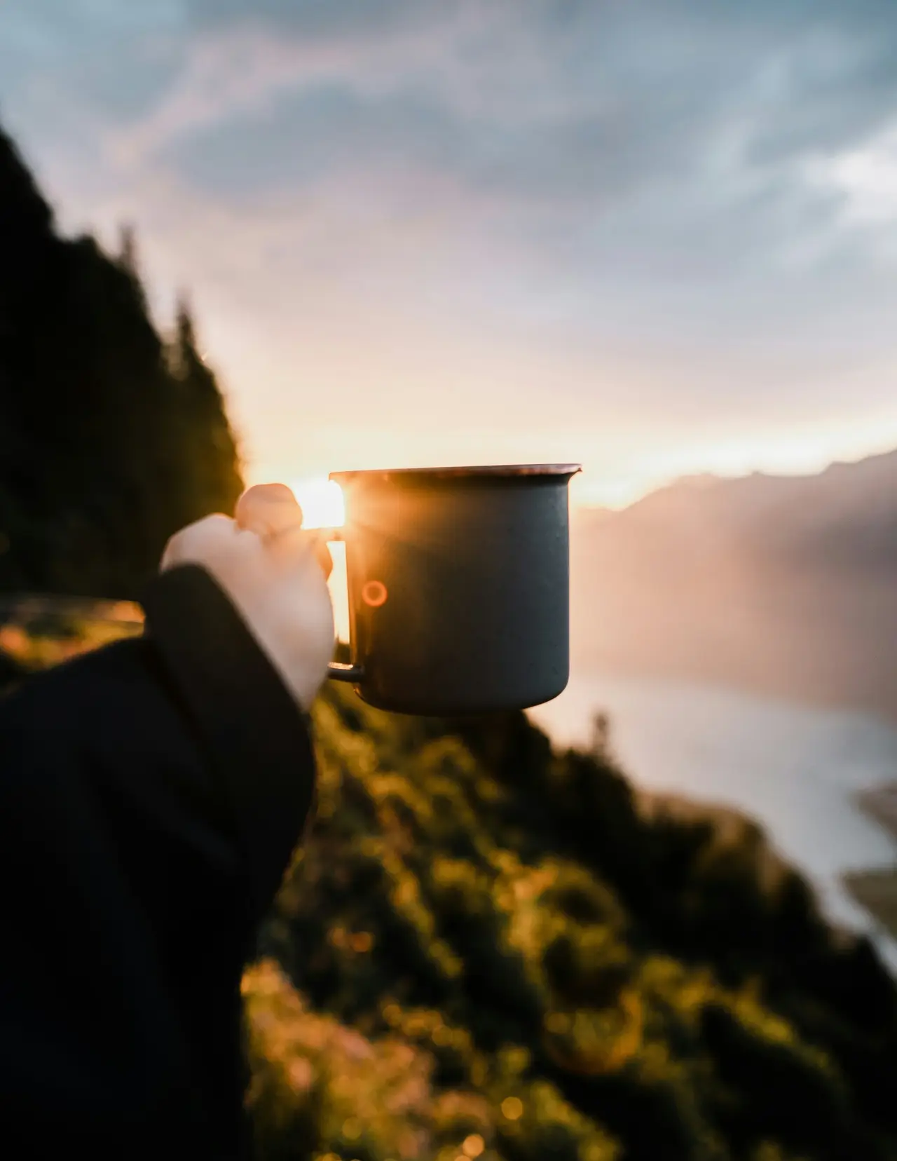 A mug held up against a mountain sunset