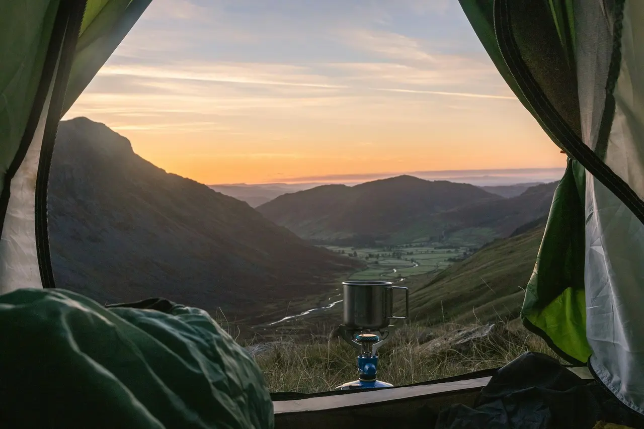 The view from a tent door over a valley, a camp stove in front